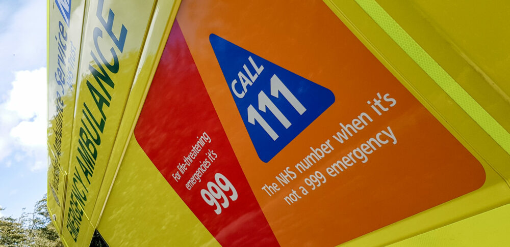 Side of ambulance with a sign that says 'call 111 when it's not an emergency'